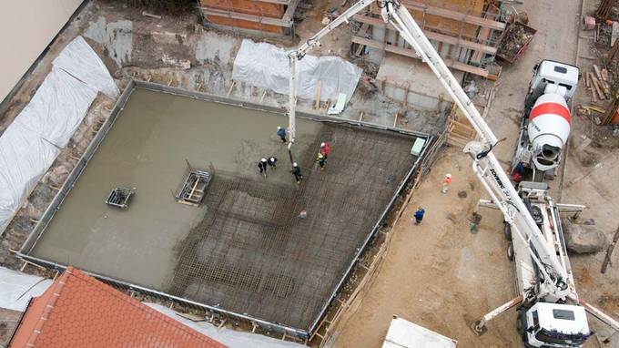 Bird's eye view of construction foundation, next to it white construction vehicle with long crane (opens enlarged image)