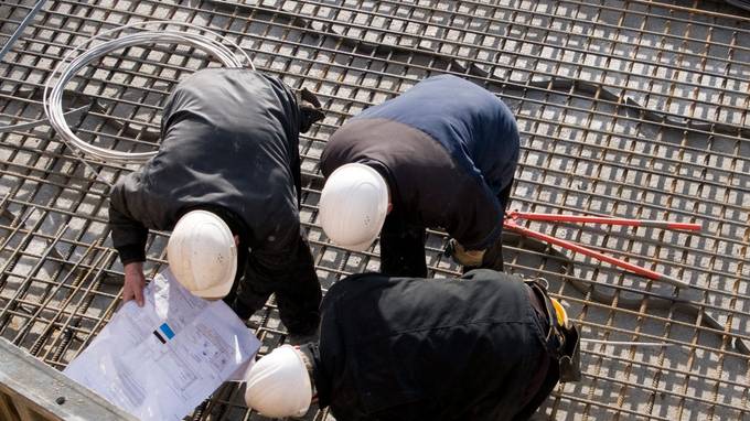 Bird's eye view of three construction workers bent over something (opens enlarged image)