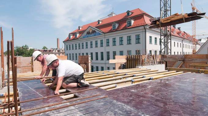 Two kneeling construction workers are busy with floor slabs (opens enlarged image)