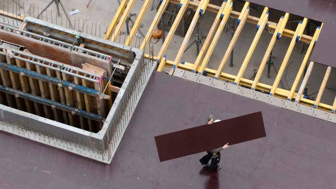 Bird's eye view of a construction worker carrying a plate over his head (opens enlarged image)