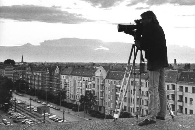 Schwarz-weiß Fotografie eines Mannes, der auf einem Dach mit einer altmodischen Kamera filmt