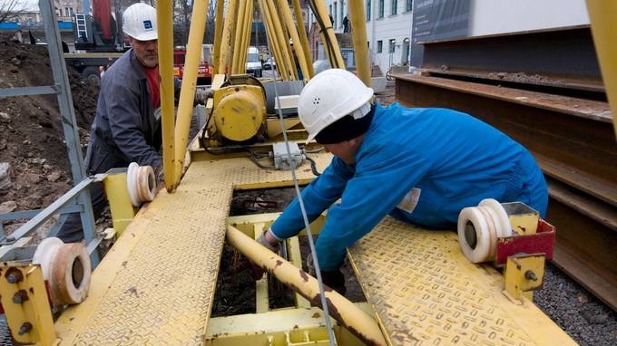 Zwei Bauarbeiter arbeiten an einem gelben Stahlgerüst (öffnet Vergrößerung des Bildes)