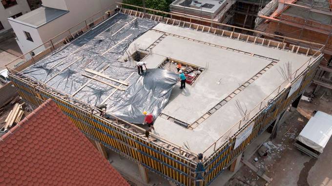 Bird's eye view of shell being covered with tarpaulins by construction workers (opens enlarged image)