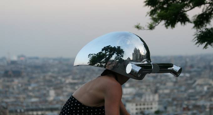 Frau mit einem silbernen Helm mit Röhrenaugen fährt auf Fahrrad durch Paris.