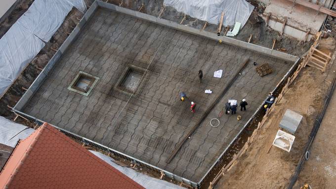 Bird's eye view of a construction site foundation with several construction workers on it (opens enlarged image)