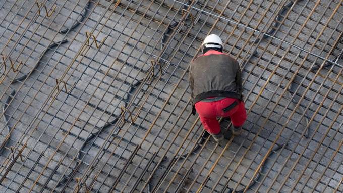 Vogelperspektive auf Bauarbeiter auf mit Stahl bedecktem Baufundament (öffnet Vergrößerung des Bildes)