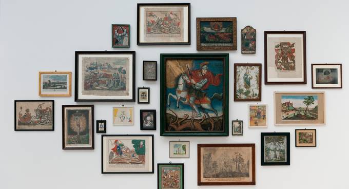 Ansammlung von Bildern mit historischen Darstellungen an einer Wand