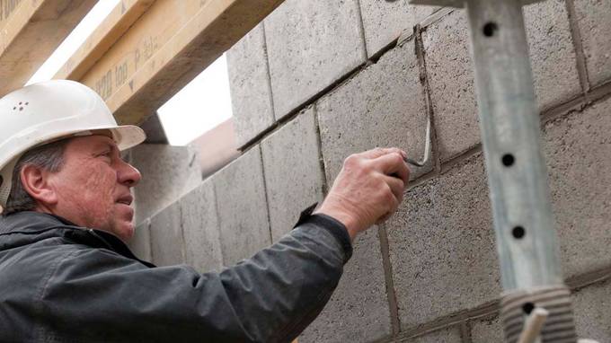 Nahaufnahme eines Bauarbeiters beim Spachteln einer Mauer (öffnet Vergrößerung des Bildes)