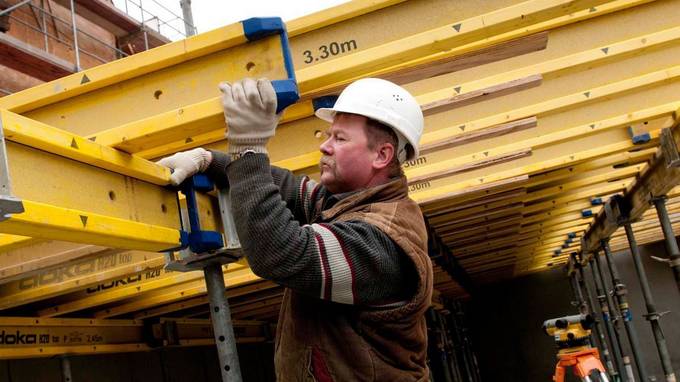 A construction worker works on yellow steel beams (opens enlarged image)