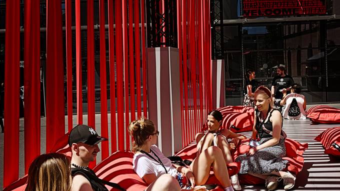 Sich ausruhende Menschen auf roten Sitzsäcken unter freiem Himmel mit Sonnenschutz (öffnet Vergrößerung des Bildes)